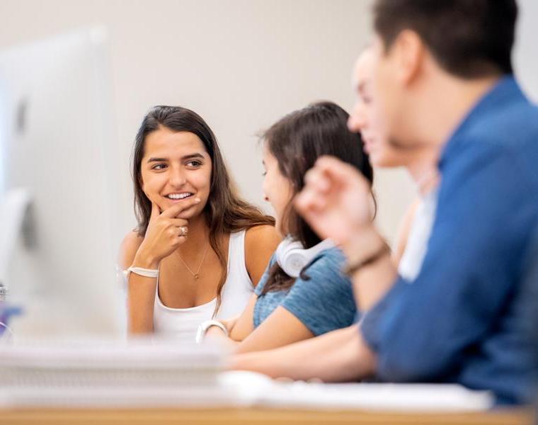 Students sit in front of a computer