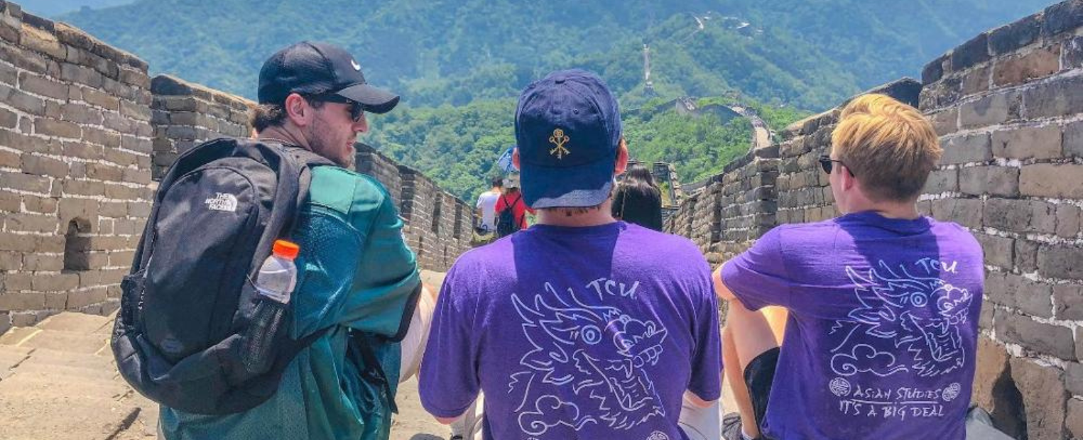 Three students sitting on Great Wall of China.