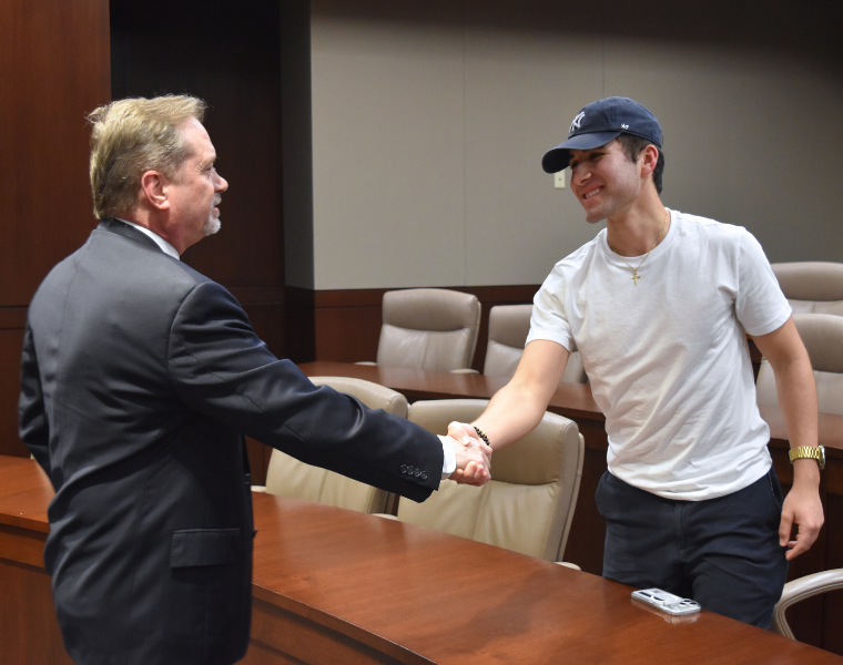 TCU alumnus Harry “Hap” Weitzel shakes the hand of a TCU student.
